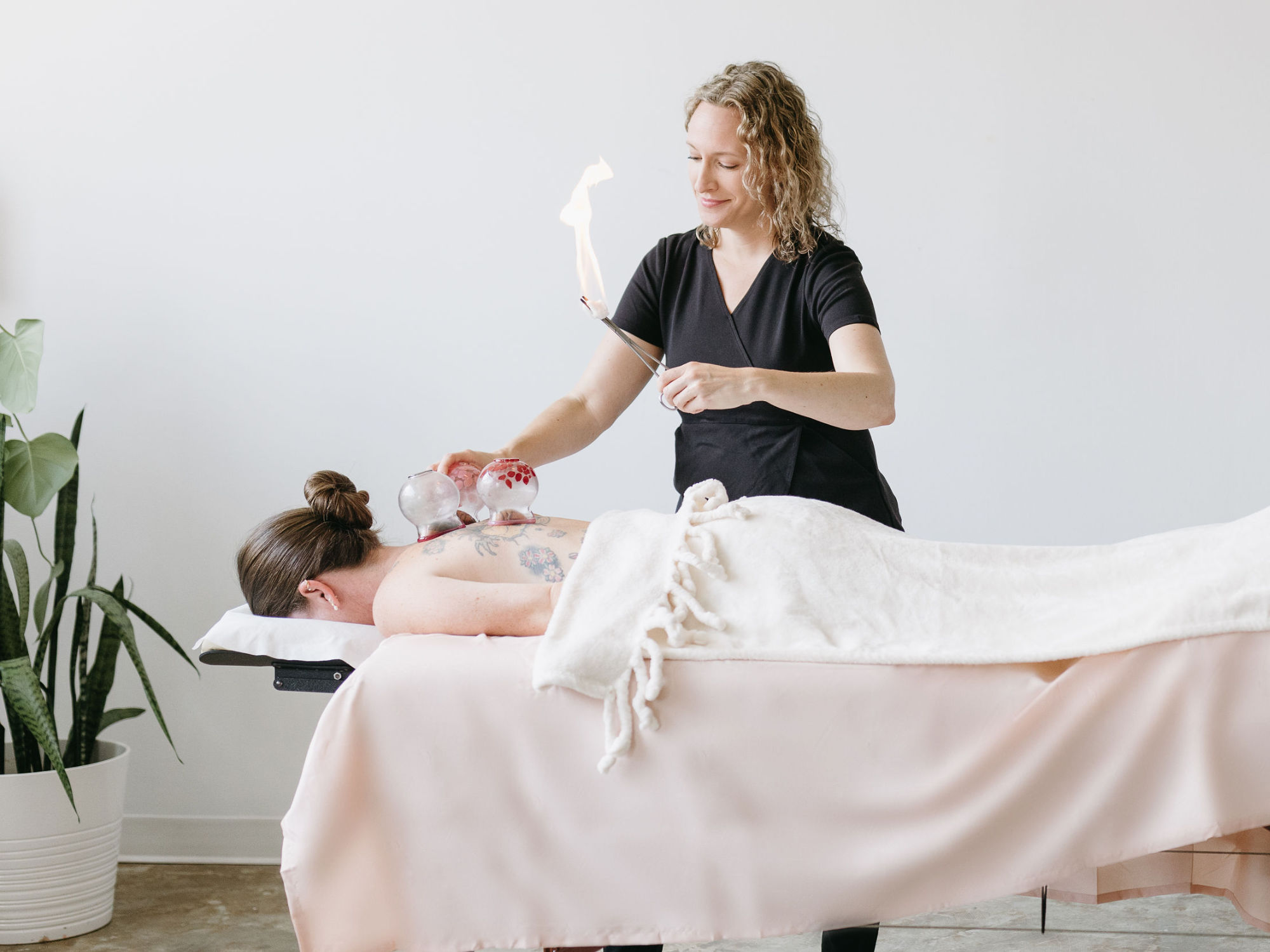 Acupuncturist at Cherry Blossom Healing Arts giving a cupping therapy treatment to a women laying face down